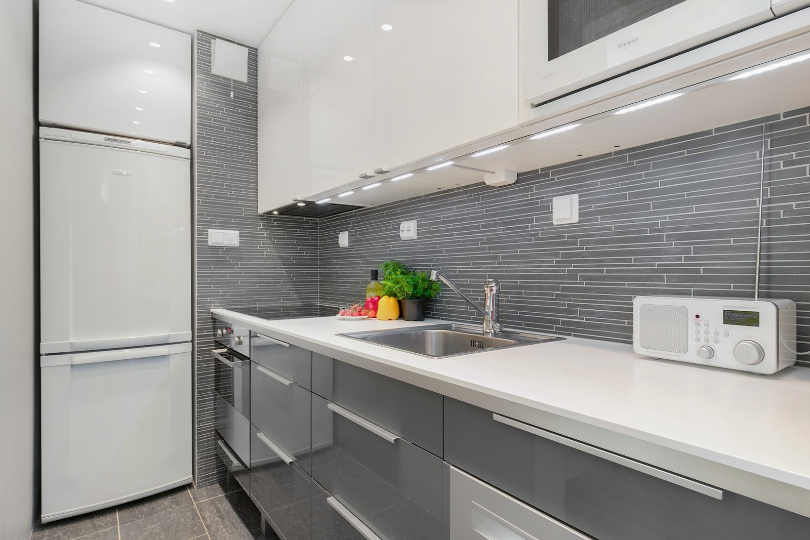 Lekker kjøkkeninnredning fra IKEA ny i 2014 med høyglans fronter, laminat benkeplate, fliser over bank og integrert komfyr, platetopp og oppvaskmaskin. Galleribilde