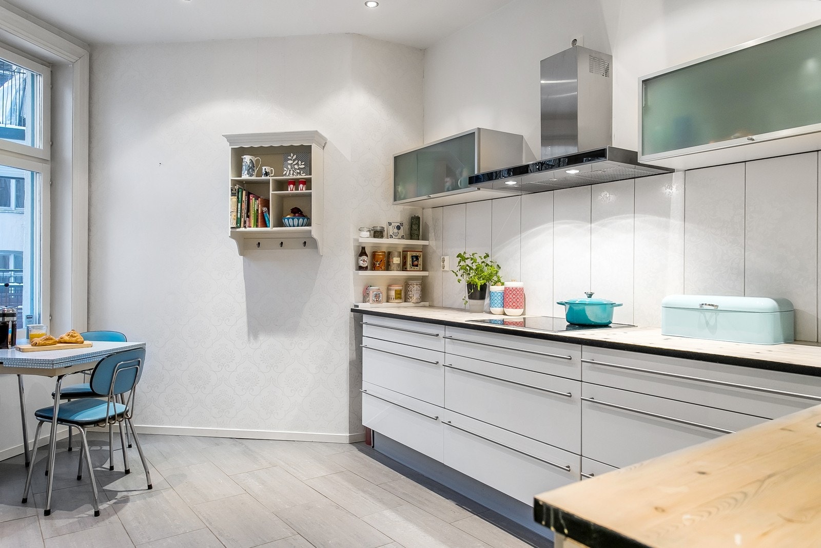 Pen kjøkkeninnredning med hvite høyglansfronter og håndtak i stål. Galleribilde