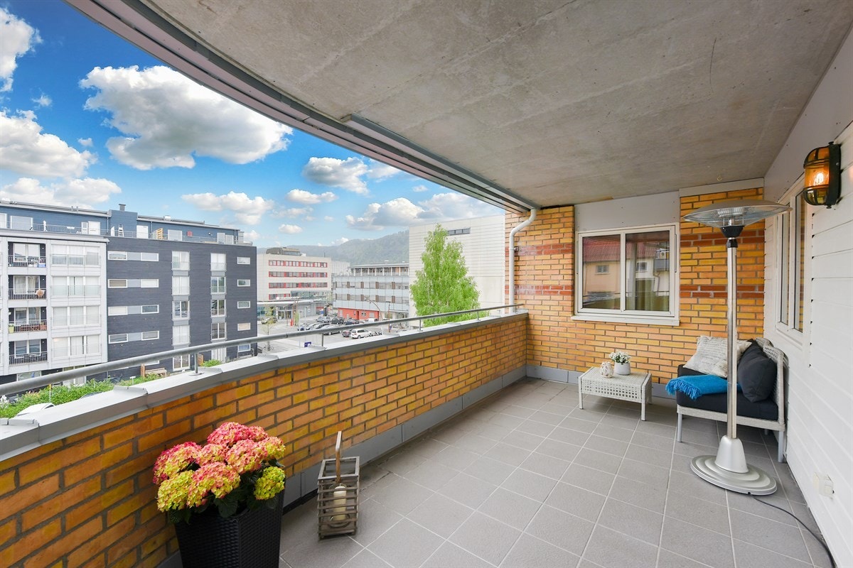 Leiligheten har en stor flislagt overbygd veranda. Galleribilde
