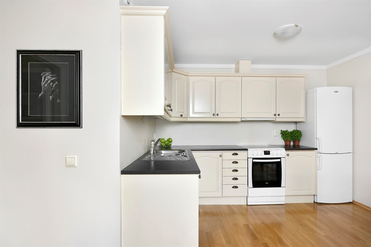 Kjøkkeninnredningen har lyse profilerte fronter og laminert benkeplate med oppvaskkum. Galleribilde