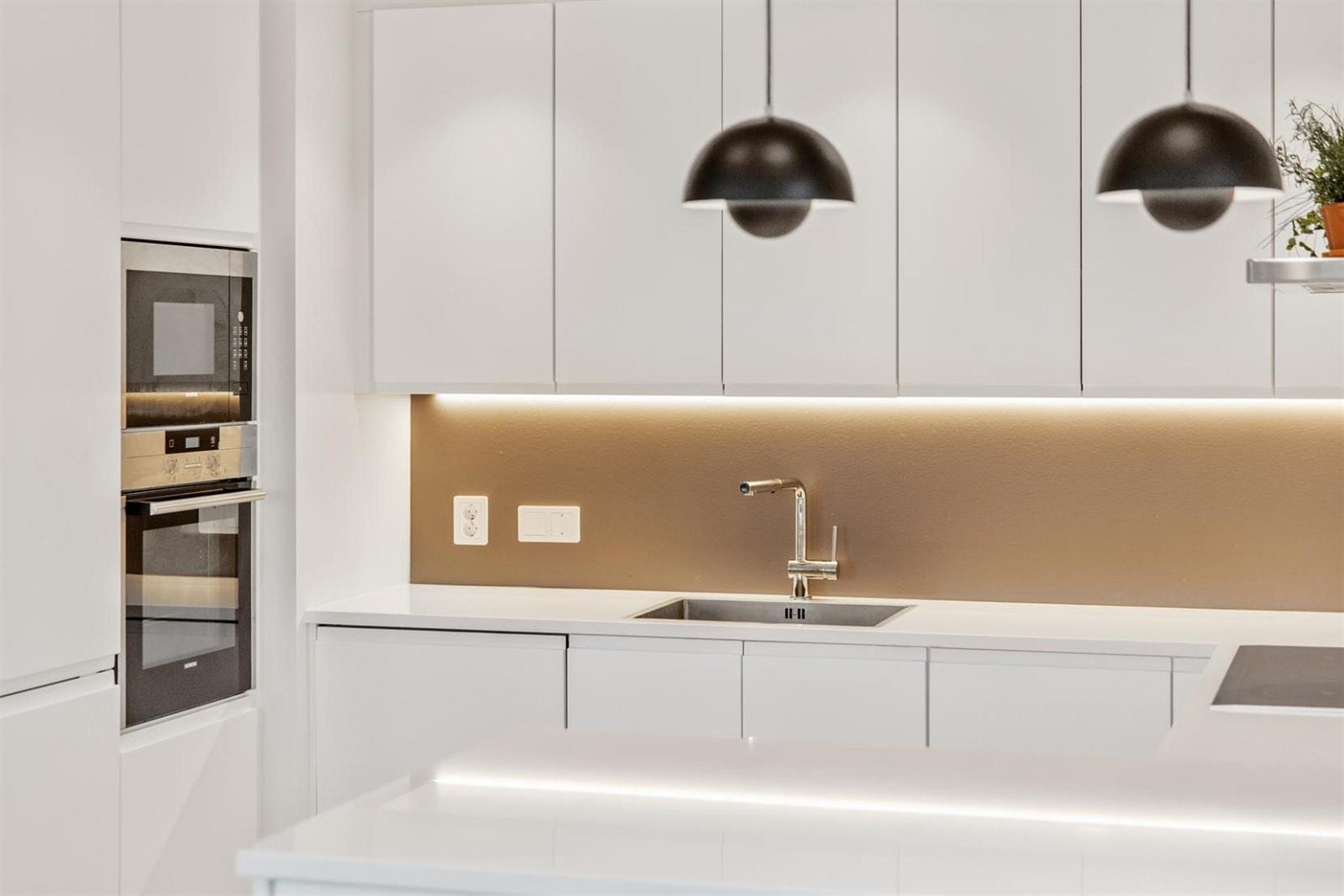 Lekker innredning fra JKE Kjøkken med slette fronter i hvit utførelse og benkeplatee i Silestone. Galleribilde
