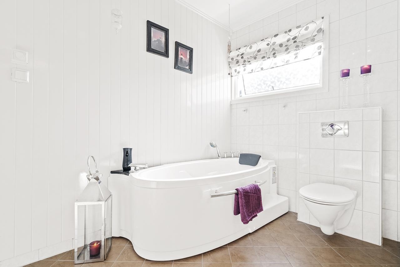 Pent flislagt bad m/varme i gulv. HJørnebadekar samt vegghengt wc Galleribilde