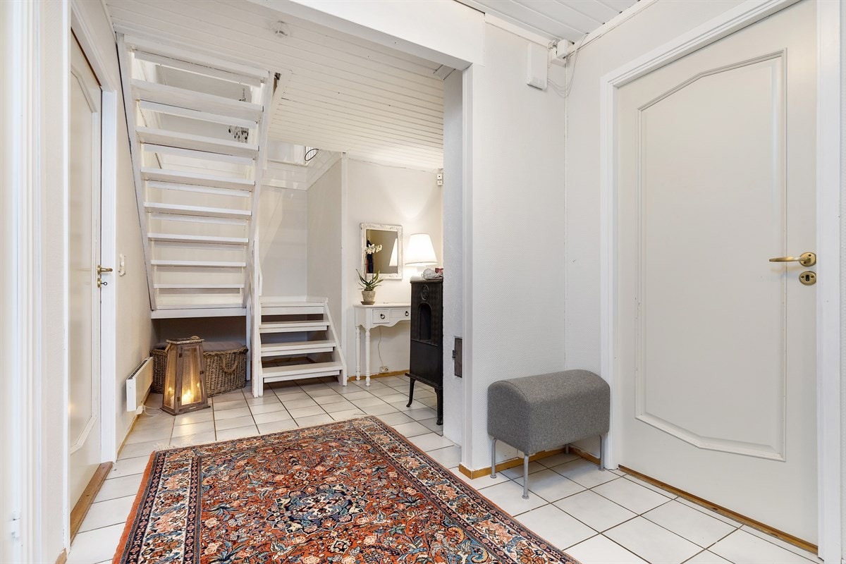 Fra et flislagt vindfang med garderobeløsning går det videre innover til en lys og luftig gang Galleribilde