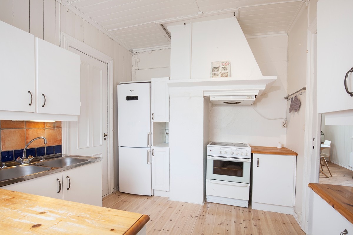 Trelakkert benkeplate og flisbelagt vegg bak vask Galleribilde