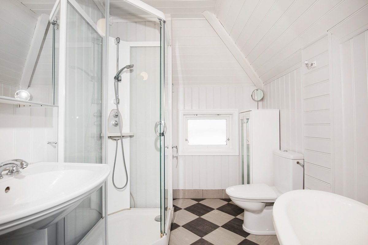 Badet er innredet med lyse vegger, søylevask, toalett, opplegg for vaskemaskin, dusj og badekar i lekker stil. Galleribilde