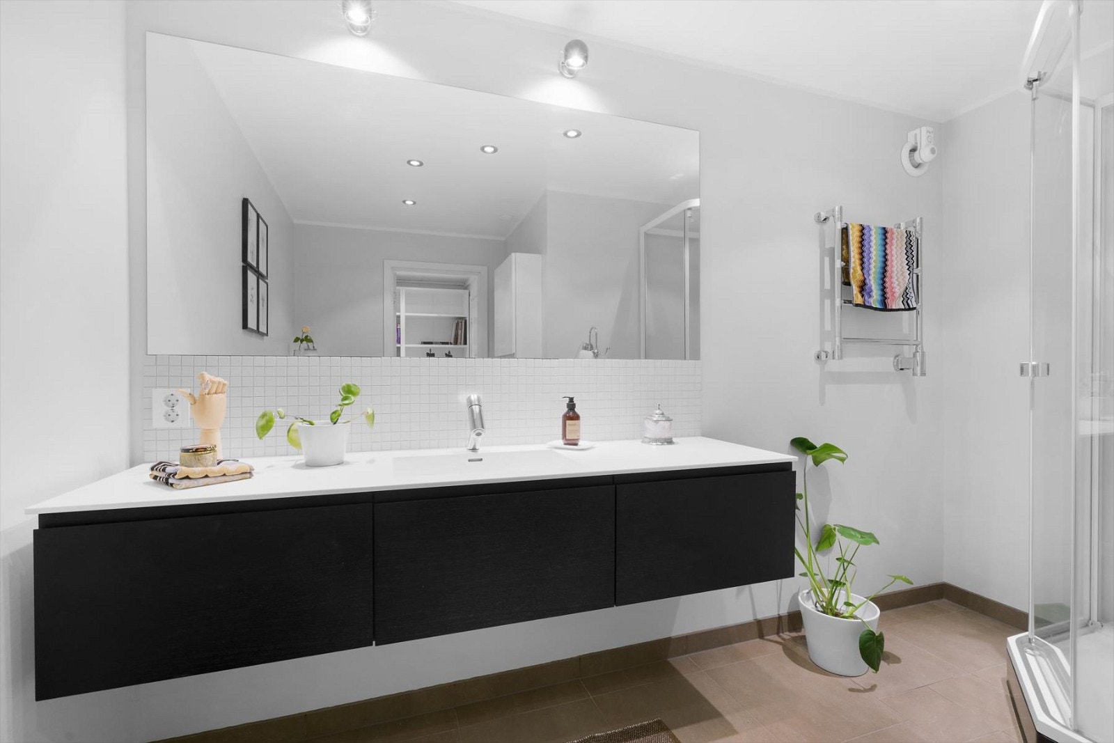 Badet er stilfullt innredet med stor innredning, dusjkabinett og vegghengt wc Galleribilde