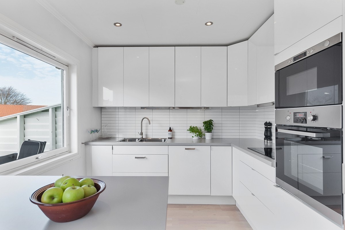 Lys og moderne kjøkkeninnredning i hvite, slette fronter og grå laminert benkeplate Galleribilde