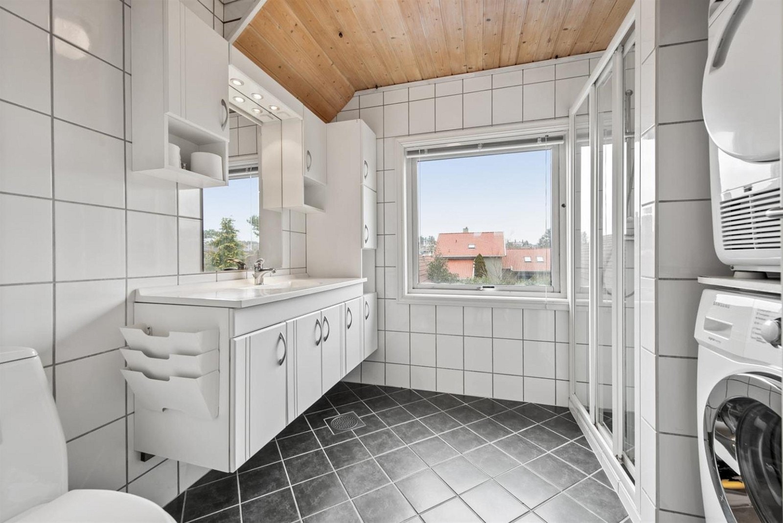 Badet er innredet med toalett, dusj og seksjon med vask. God plass til vaskemaskin og tørketrommel. Galleribilde