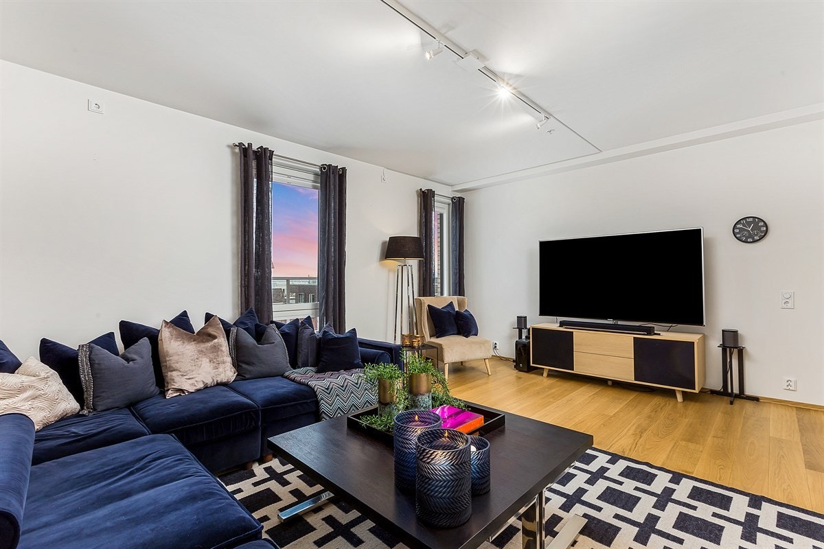 Tv-stuen har enstavs eikeparkett, hvitmalte overflater, og spotbelysning. Det kjærkomne oppholdsrommet ligger i forlengelse av hallen, og en tofløyet skyvedør med frostet glass gjør det mulig å trekke seg tilbake med en god film. Galleribilde