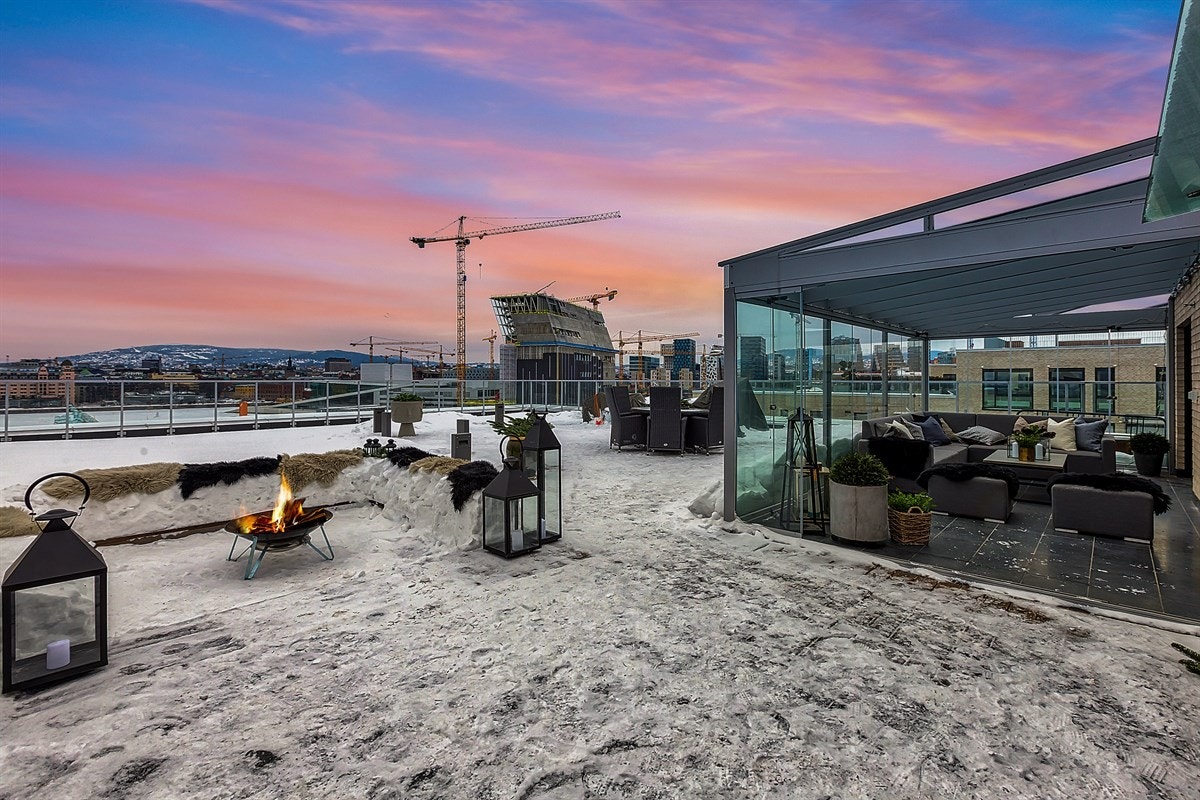 Terrassen på 153 kvm er vakkert opparbeidet med stor platting og belysning, og en liten hageflekk tilbyr gress og sedum under føttene. Her oppe på taket kan man trekke seg tilbake i lune omgivelser innenfor vinterhagens glassfasade, eller nyte solen ute p Galleribilde