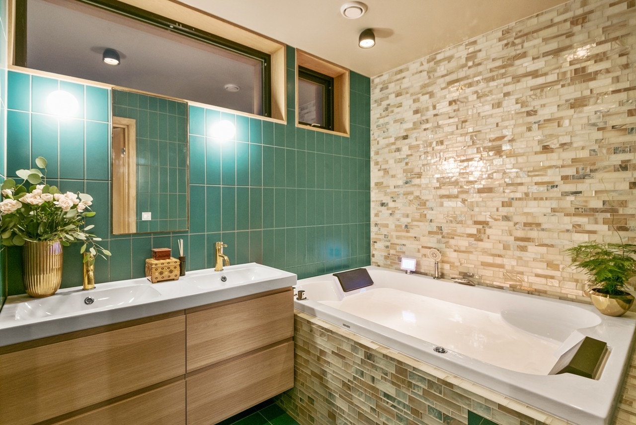 Det flislagte badet i første etasje fremstår som et herlig velværebad med veggmontert toalett, innfliset badekar, samt dusjnisje med forgylt regnfallsdusj og flislagt sittebenk. Galleribilde