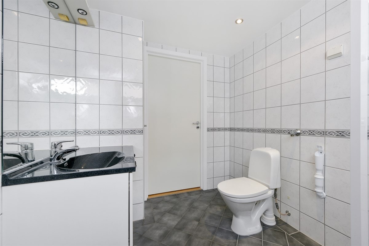 Badet er delikat med hvite veggfliser og grå gulvfliser, samt gulvvarme og downlights. Galleribilde
