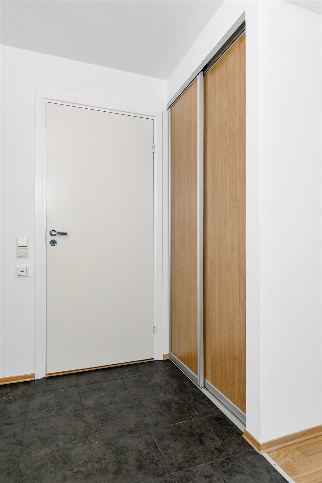 Entreen harmonerer fint med resten av leiligheten med sorte gulvfliser og hvitmalte veggflater. Galleribilde