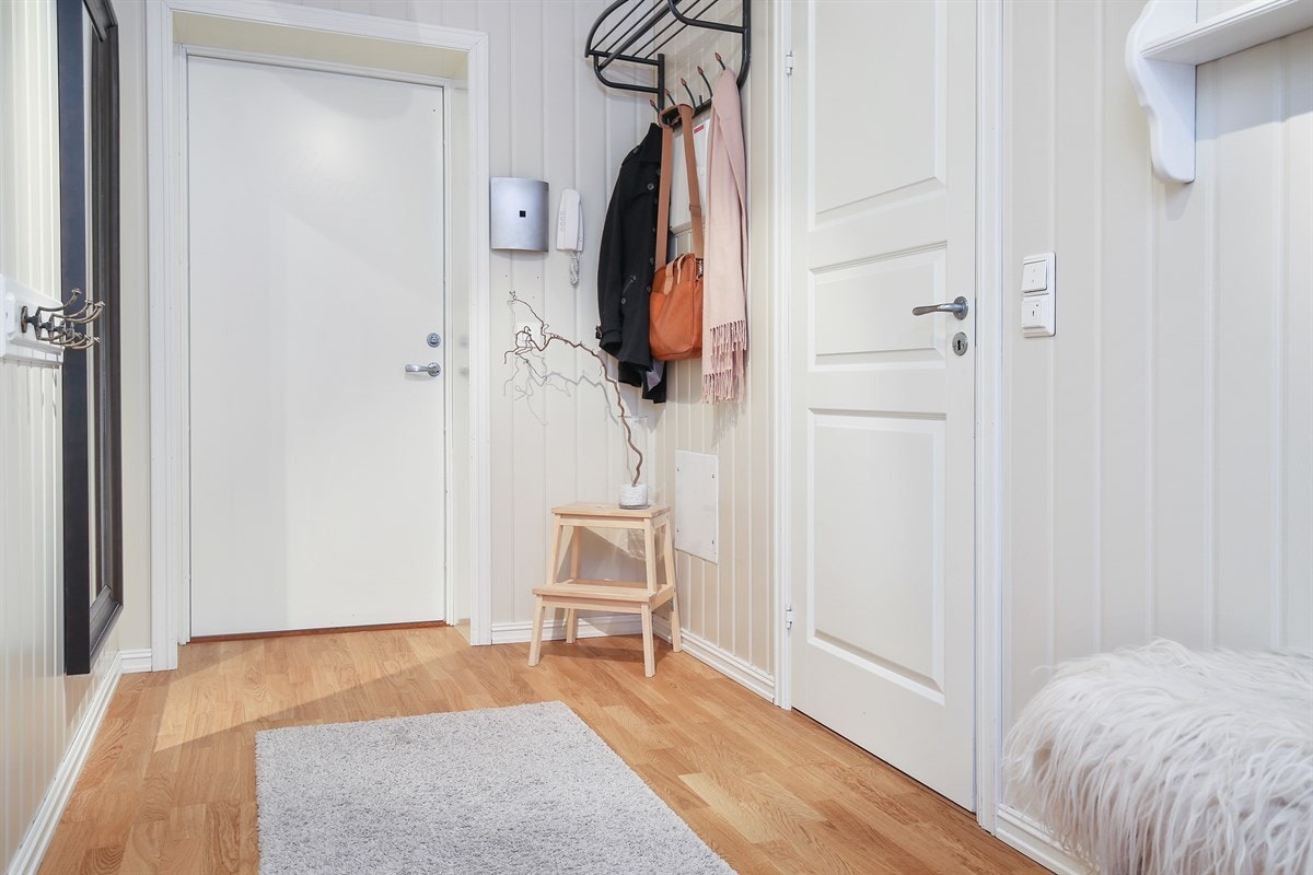 Entreen har parkett på gulv, belysning i himling og panelte vegger i dus farge, noe som gir et innbydende førstemøte med leiligheten. Galleribilde