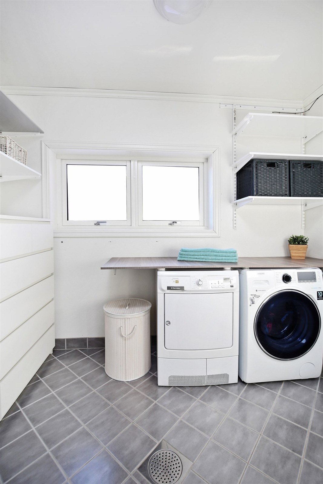 Bak skyvedør på bad 1 finner du en praktisk vaskeromsdel i samme stil som badet. I rommet er det montert hyller og en fin arbeidsbenk som danner nisje for vaskemaskin og tørketrommel. Galleribilde