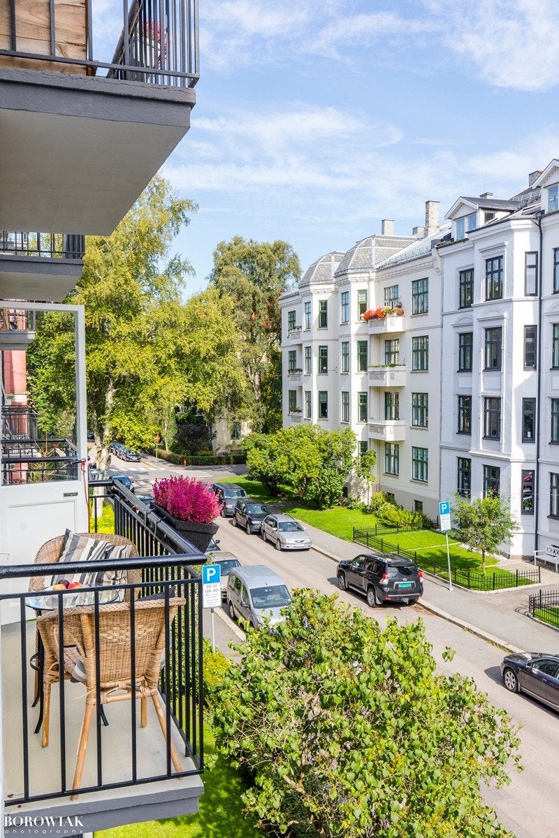 Hyggelig utsyn fra balkongen over trafikkstille gate preget av flotte forhager og klassisk bygårdsbebyggelse. Galleribilde