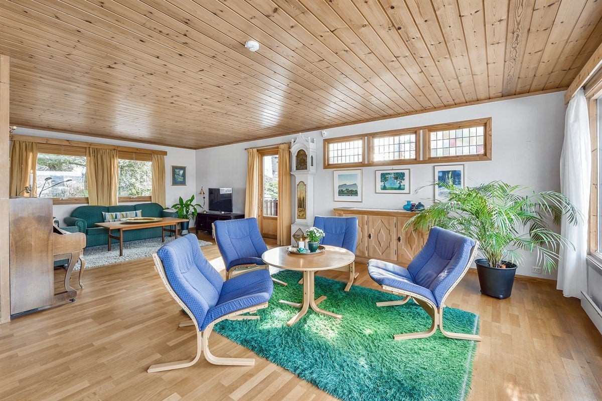 Stuen har parkett på gulv, og veggene er lyse med unntak av pipen som er kledd med teglstein. Galleribilde