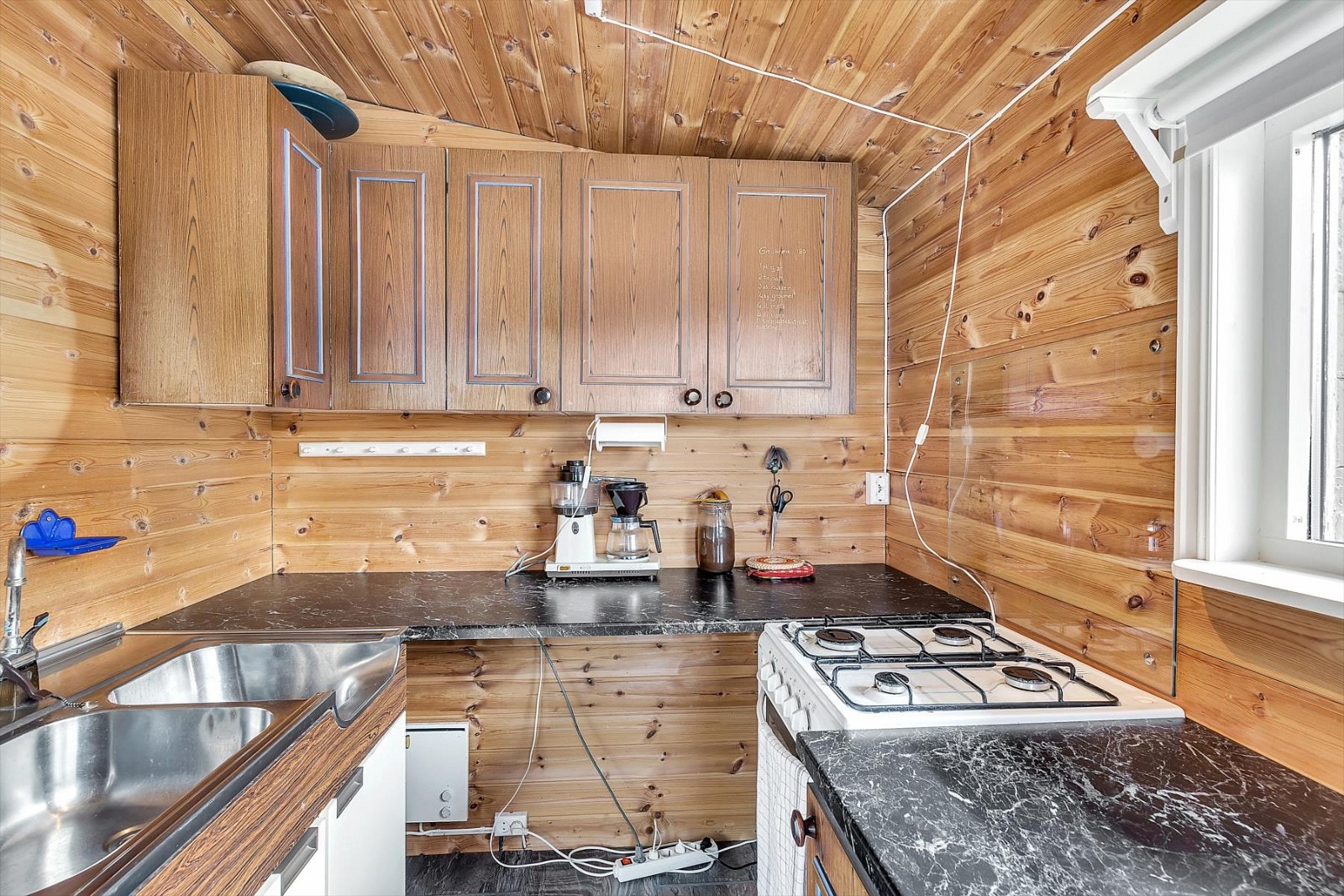 Kjøkken med overflater med laminatgulv og trepaneler på vegger og i himlinger. Galleribilde