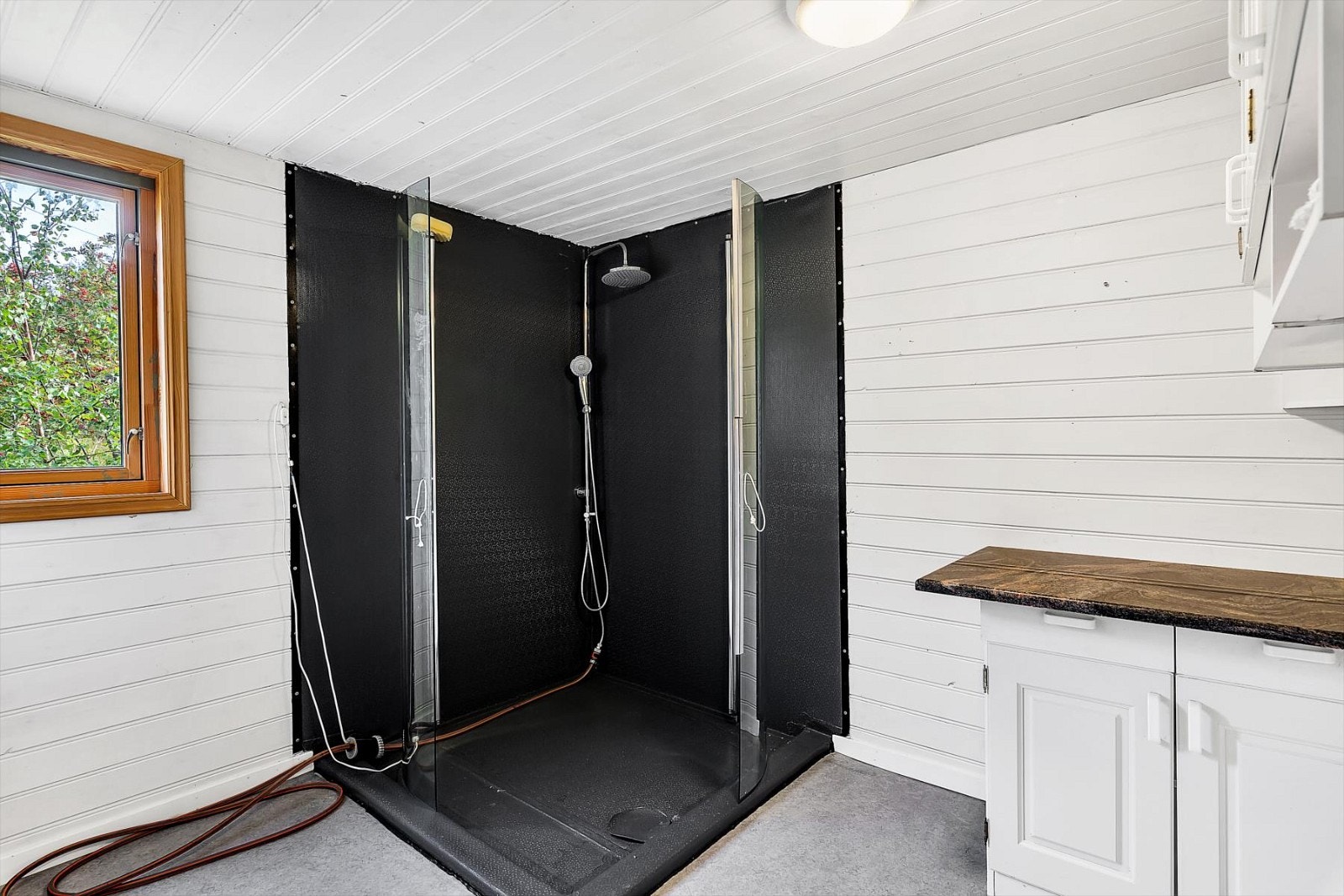 Det er etablert en "dusjsone" med buede innfellbare dusjvegger. Noen enkle skap er montert i rommet. Galleribilde