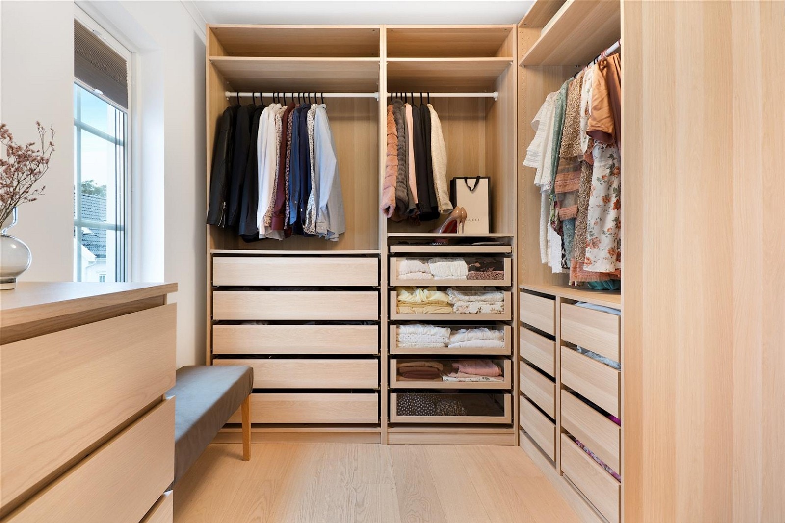 Walk-in closet er innredet med garderobeskap og kommode i lys eikefiner Galleribilde