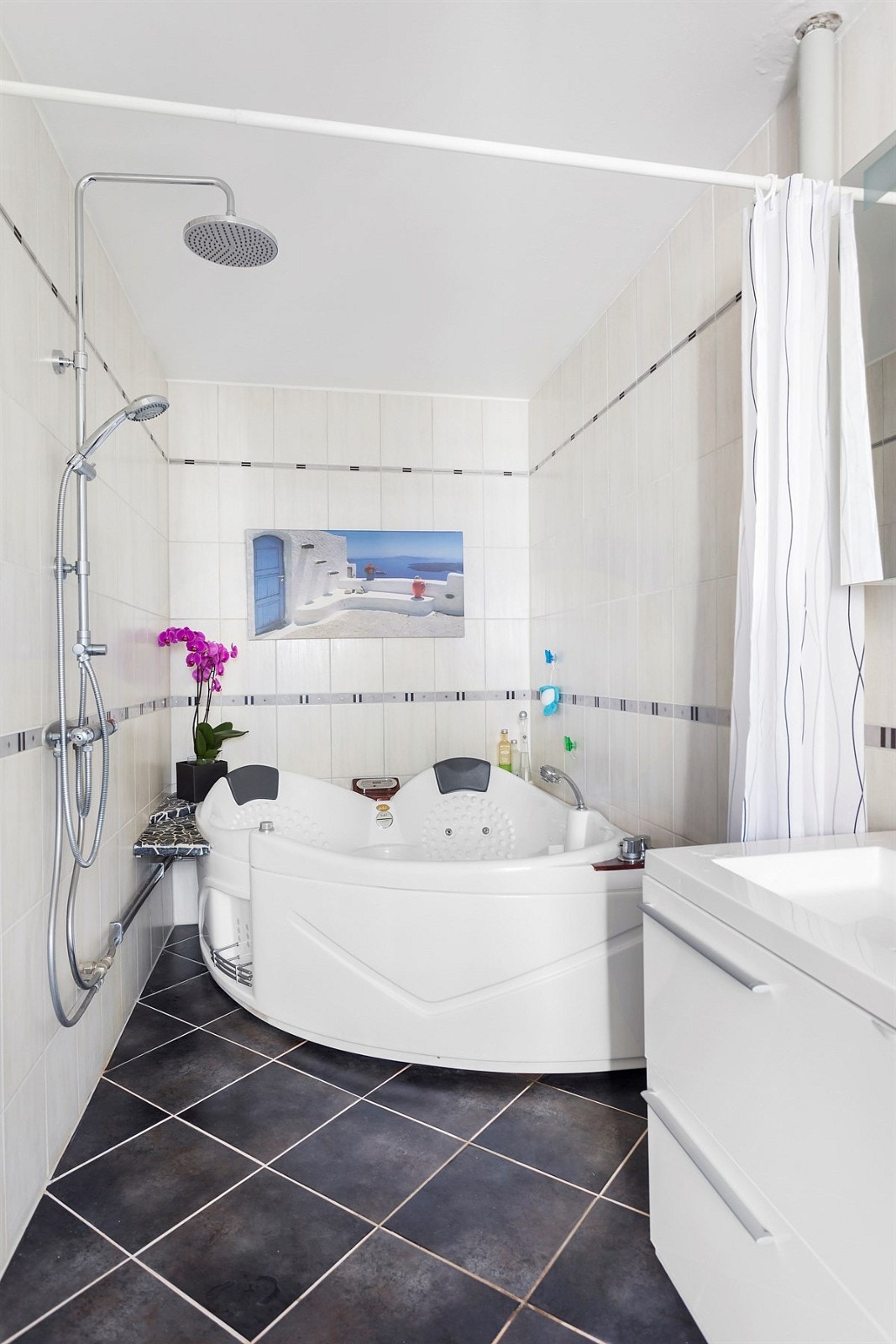 Leiligheten har et romslig bad med opplegg for dusj, hjørnebadekar, servantskap og opplegg for vaskemaskin/tørketrommel. Galleribilde