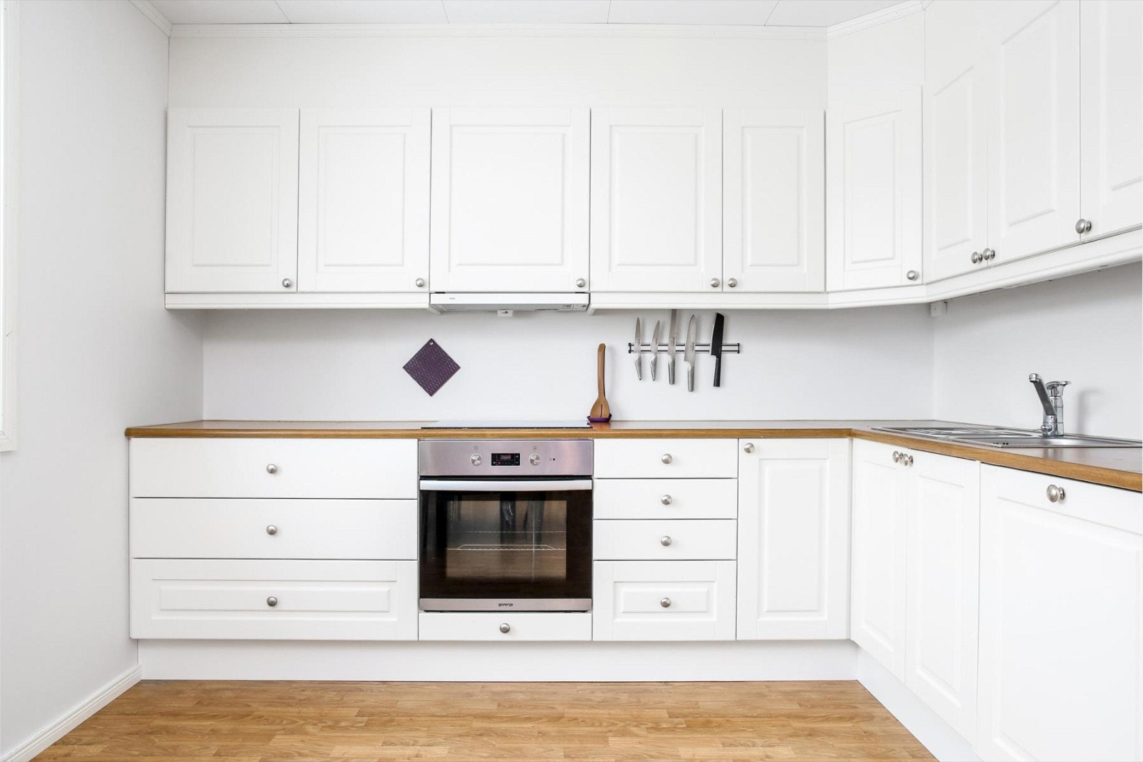 Hvit og delikat kjøkkeninnredning. God skap og benkeplass. Galleribilde