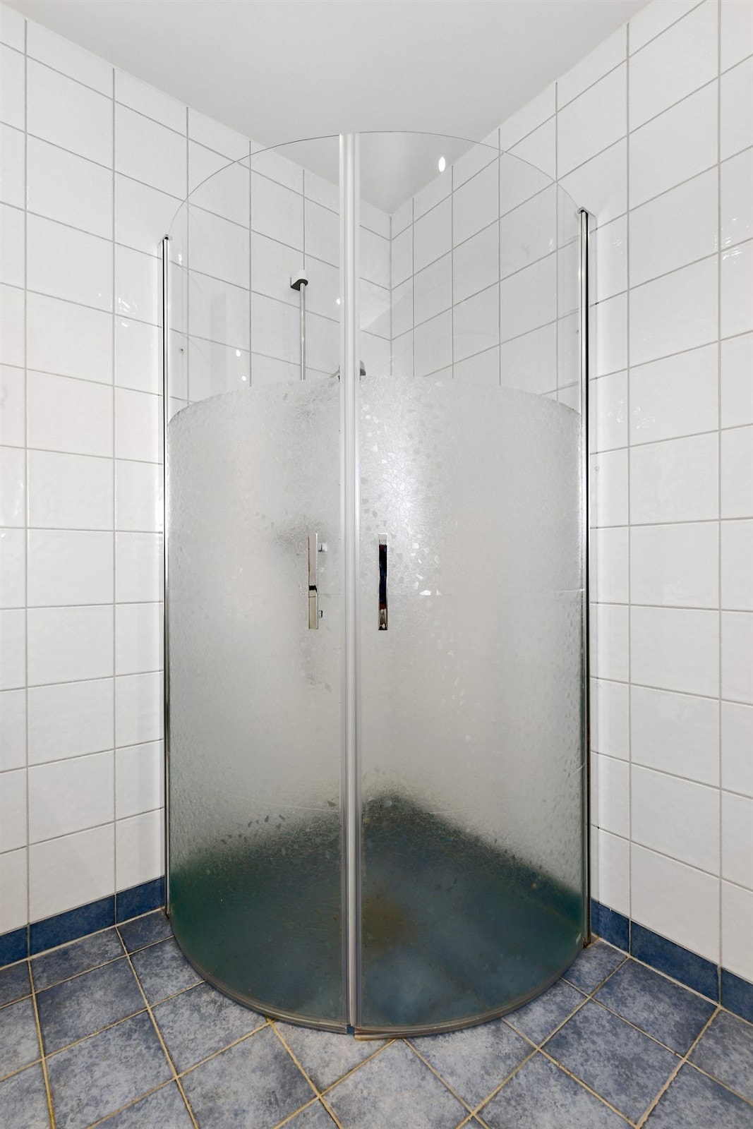 Videre er det et gulvmontert toalett, et dusjhjørne med innfellbare dører, samt opplegg for vaskemaskin og tørketrommel. Galleribilde