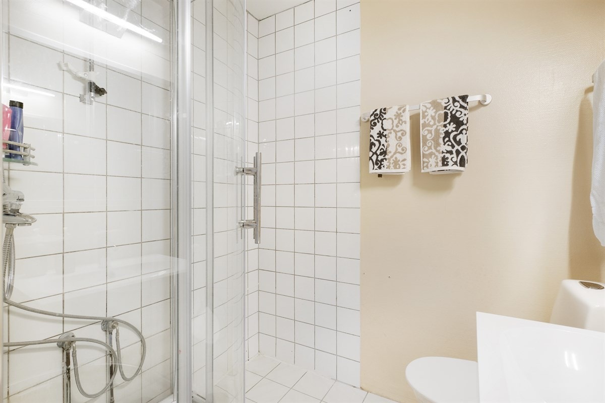 Bad med dusjhjørne og opplegg for vaskemaskin og tørketrommel. Galleribilde