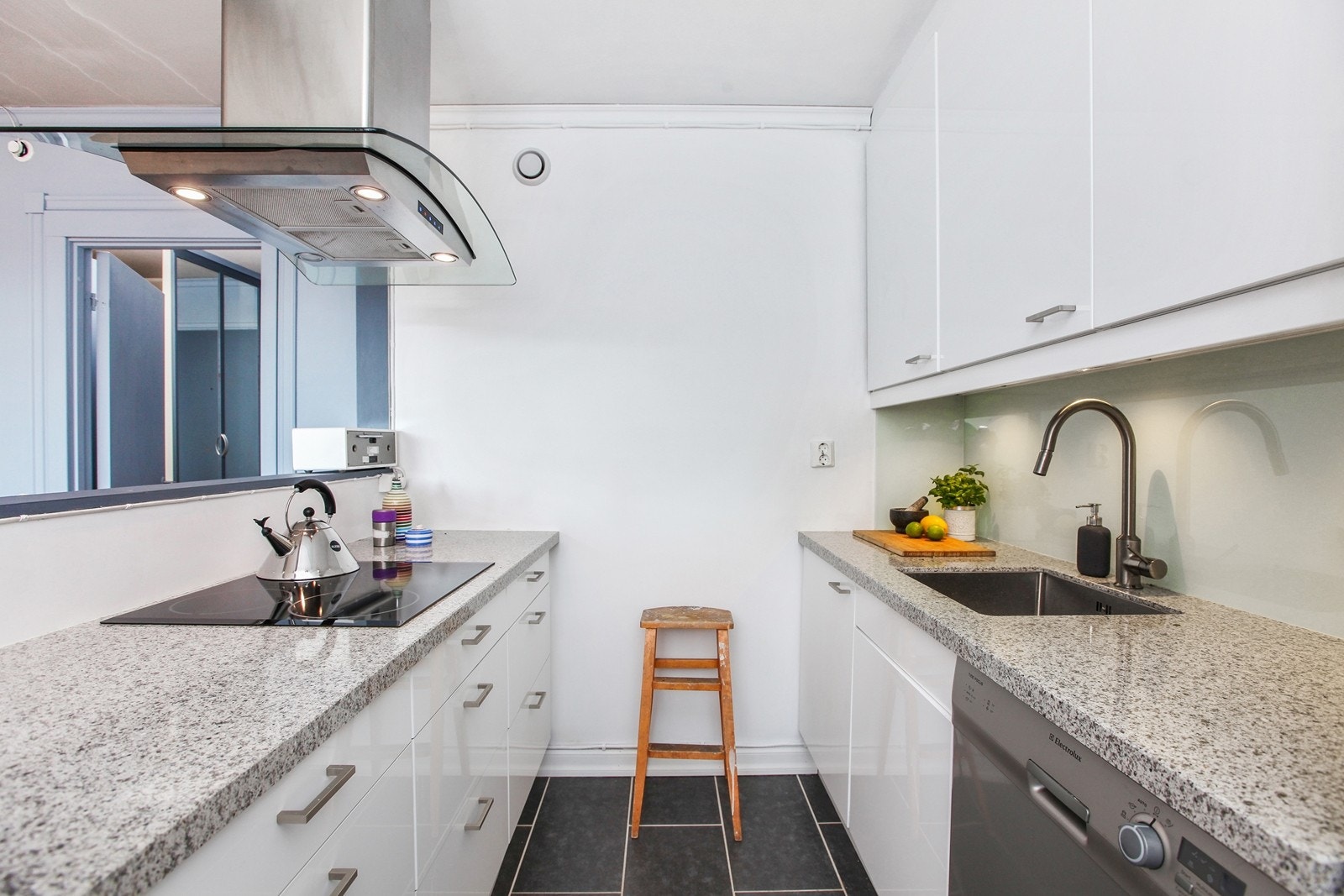 Lyst og pent kjøkken med integrerte hvitevarer. Legge merke til steinbenkeplaten. Galleribilde