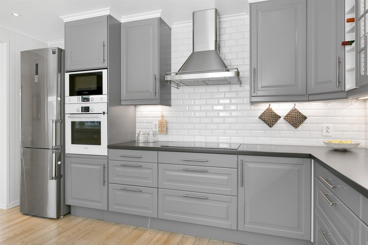 Den takhøye innredningen har grå, profilerte fronter og fine detaljer som vinhyller og vitrineskap med belysing. Galleribilde