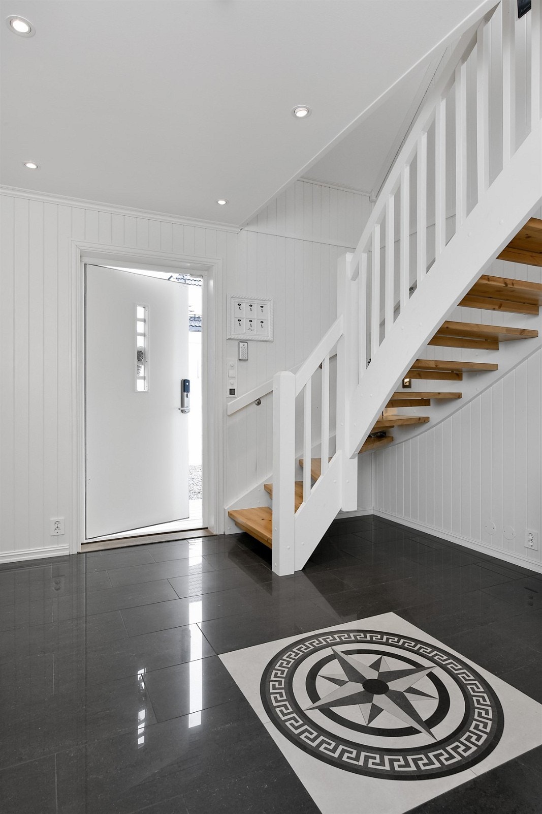 Et overbygget inngangsparti med hvitmalt ytterdør ønsker deg velkommen inn i denne flotte eneboligen. Galleribilde