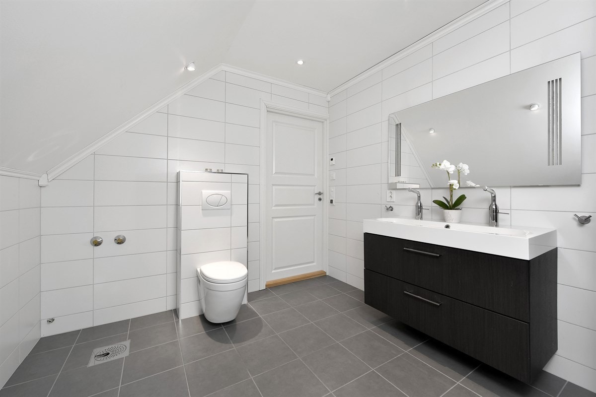 Videre er det vegghengt toalett og dusjkabinett med sotede glassdører. Galleribilde