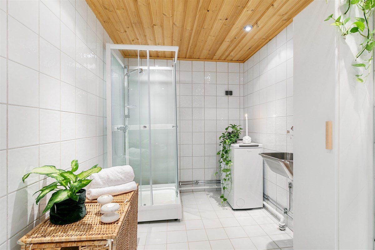 Dusjkabinett og opplegg for vaskemaskin i hjørne. Galleribilde