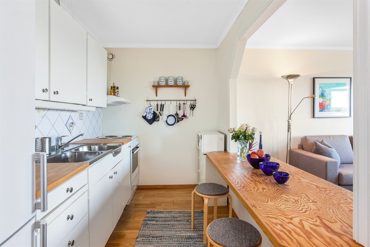 Original innredning med rustfri oppvaskkum, ventilator med filter og fliser over benkeskap. Galleribilde