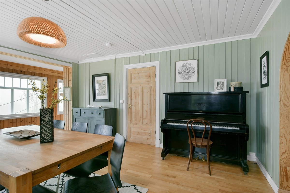 Store vinduer med bred karm tilfører lys og nostalgisk sjarm, mens en glassdør fører ut til en solrik terrasse. Galleribilde