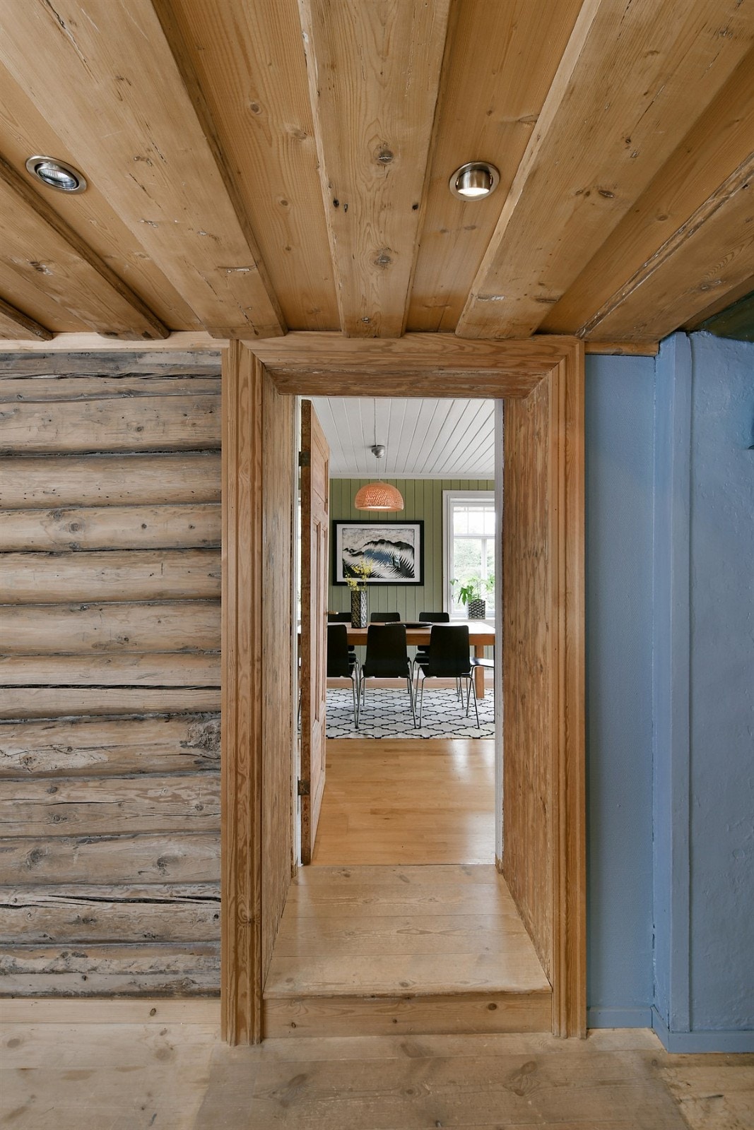 Når du går inn i boligens lune kjøkken er det som å bli satt tilbake i tid. Her er det lav takhøyde med synlige bjelker, tregulv og blåmalte vegger som står fint til solide panelvegger. Galleribilde