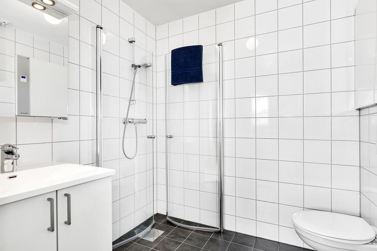 Boligen har to bad, ett i første og ett i andre etasje. Begge bad er helfliset med mørke gulvfliser og lyse fliser på veggene Galleribilde