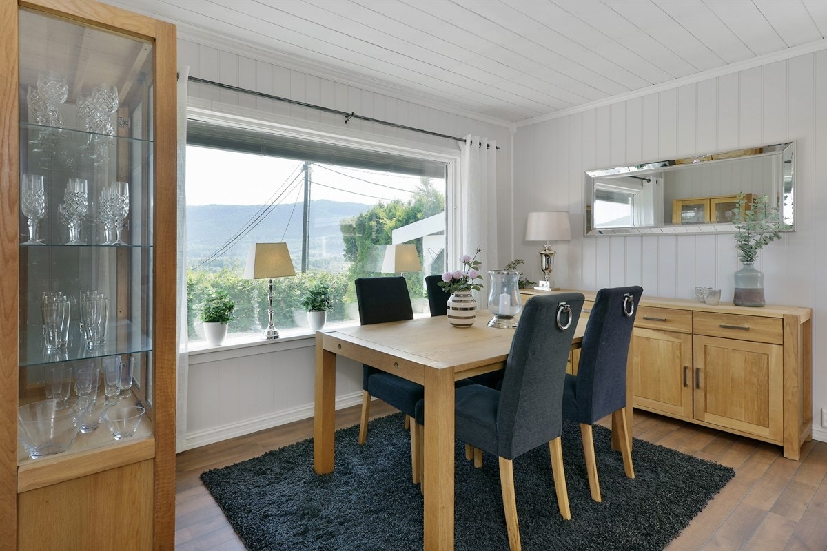 Store vindusflater på to sider åpner for dagslys og flott utsikt, mens en glassdør fører ut til deilige uteplasser og hage. Galleribilde