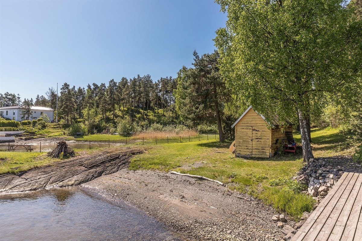 Tilgrensende eiendom, en ubebygd strandeiendom på ca. 2 mål med ca. 41 meter strandlinje, båthus og flytebrygge kan kjøpes i tillegg Galleribilde