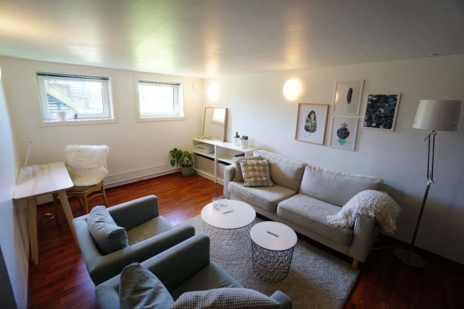 Sofagruppe med skrivebord og hyller mot vinduene. Vinduene ble byttet nylig. Disse viser på dette bildet. Galleribilde
