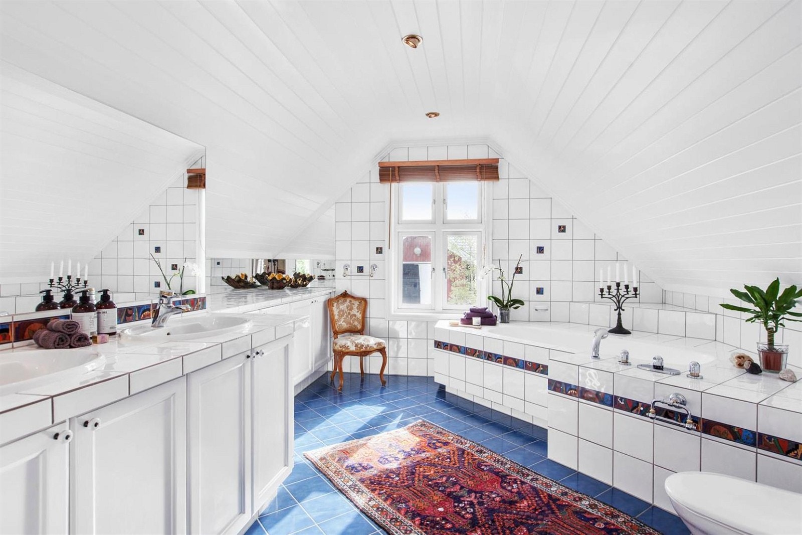 Romslig flislagt bad i 2 etg. med badekar og doble servanter. Galleribilde