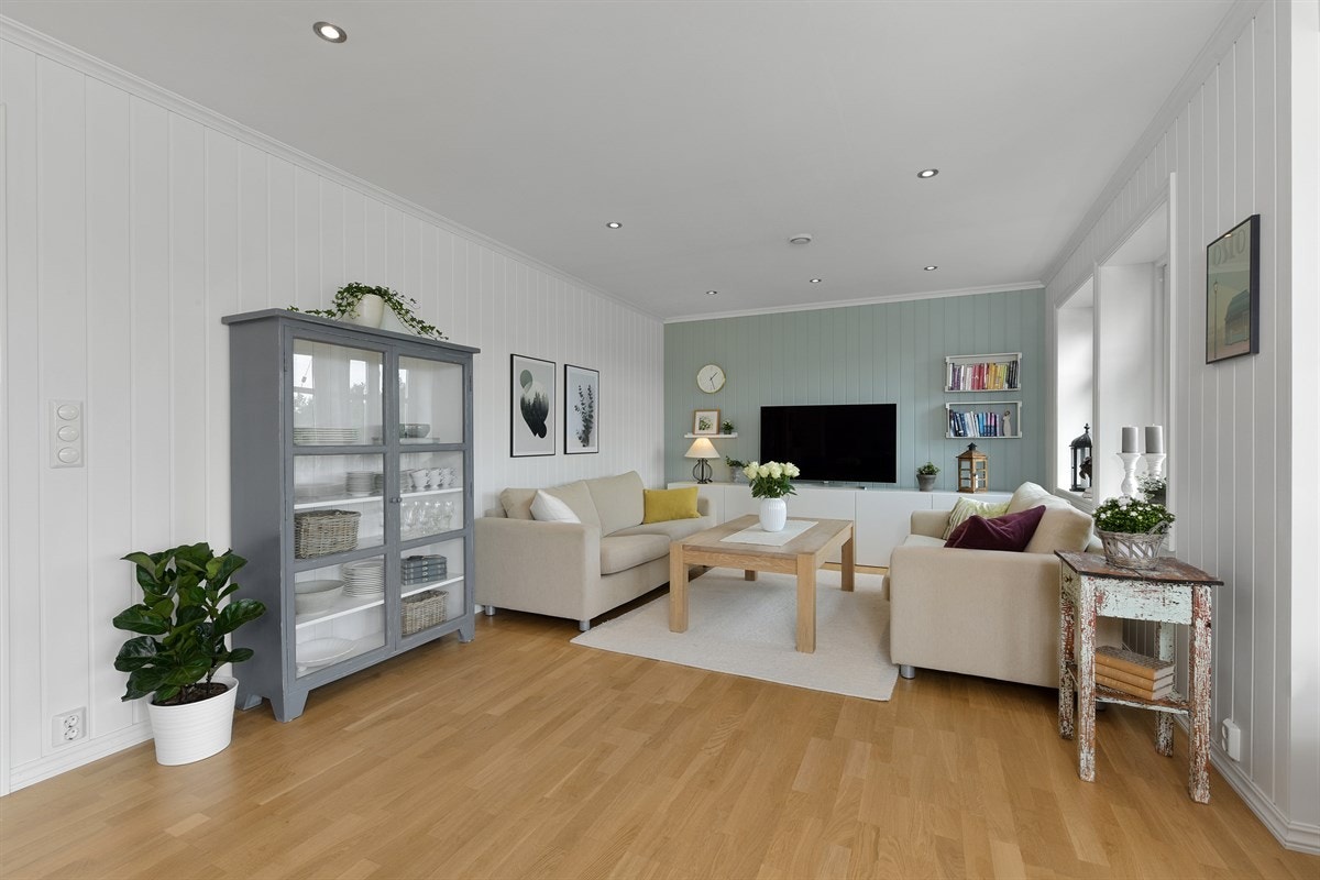 Eneboligen har en svært innbydende stue med parkett, lysmalt veggpanel med fine fondvegger på begge sider, vannbåren gulvvarme og downlights. Galleribilde