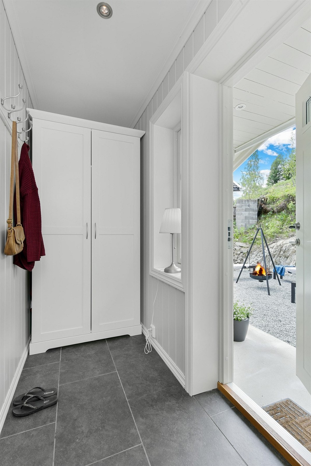 En knaggrekke er montert på veggen slik at du enkelt kan henge av deg ytterjakken og et hvitt garderobeskap gir godt med lagringsplass for klær og sko. Galleribilde