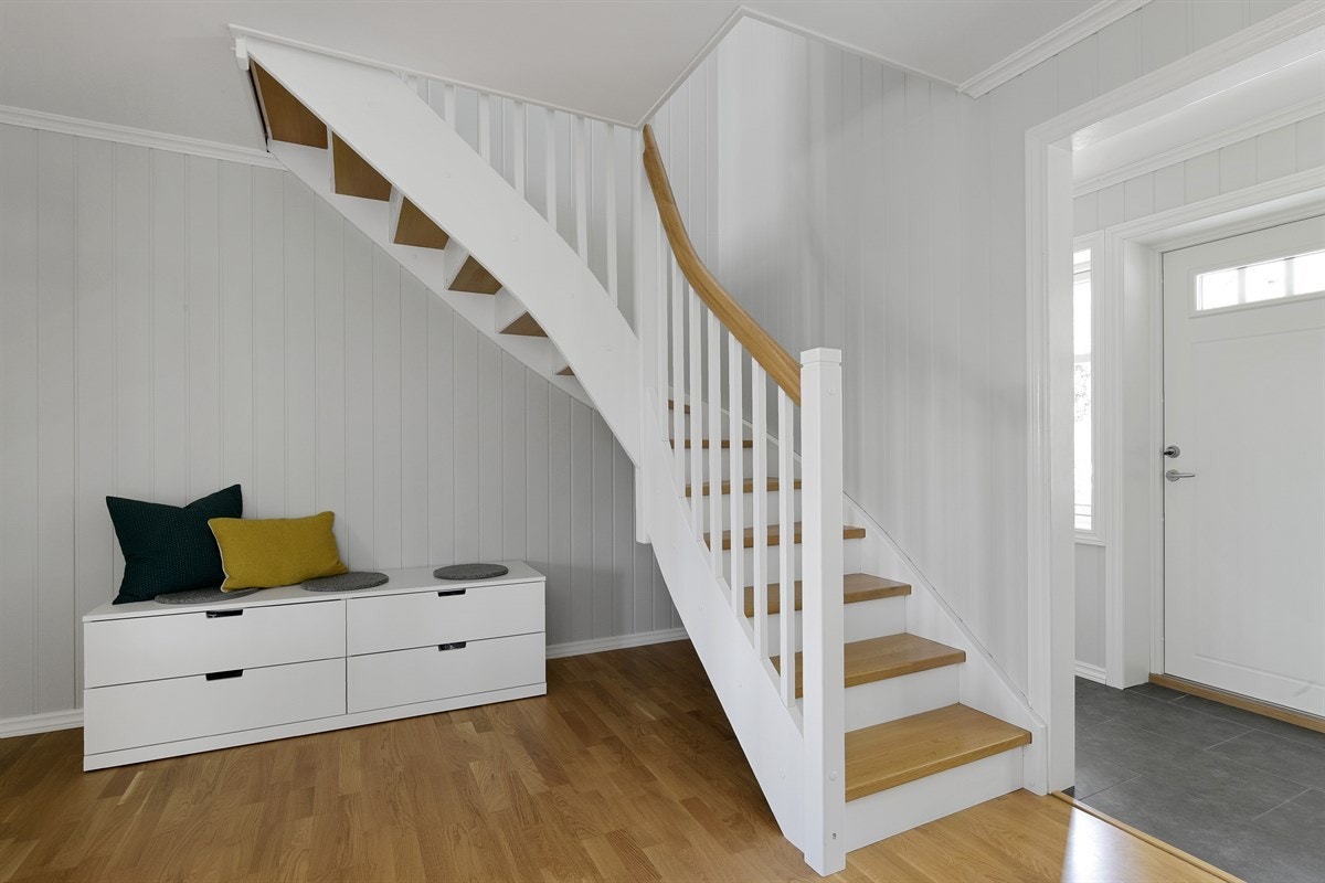 En hvitmalt trapp med eiketrinn gir adkomst til andre etasje. Under trappen kan man man evt. opprette en bod for ytterligere lagringsplass. Galleribilde