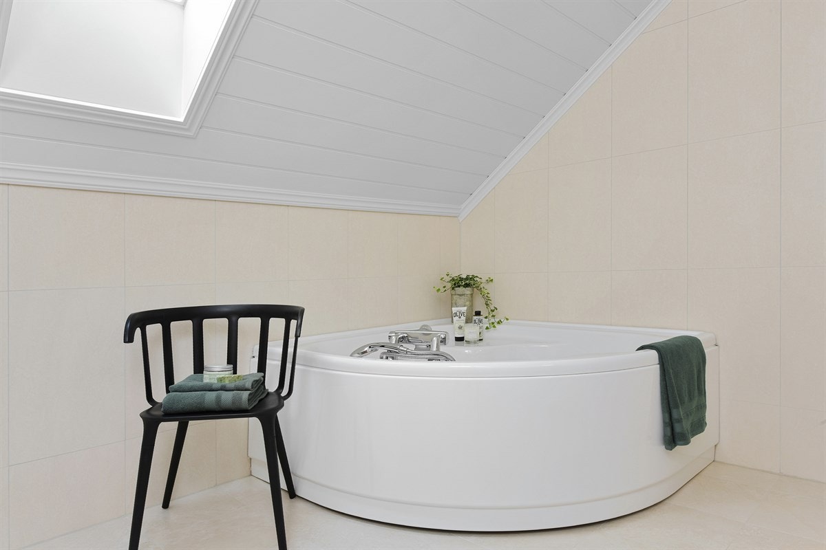 Badet er utstyrt med veggmontert toalett, dusjhjørne og et deilig hjørnebadekar. Galleribilde