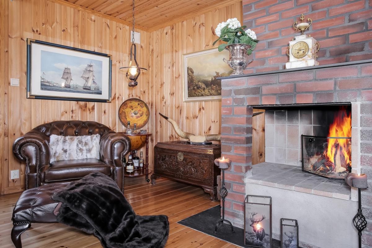 Peisestuen har en flott plassmurt peis i teglstein med peishylle og stål plate på gulv Galleribilde