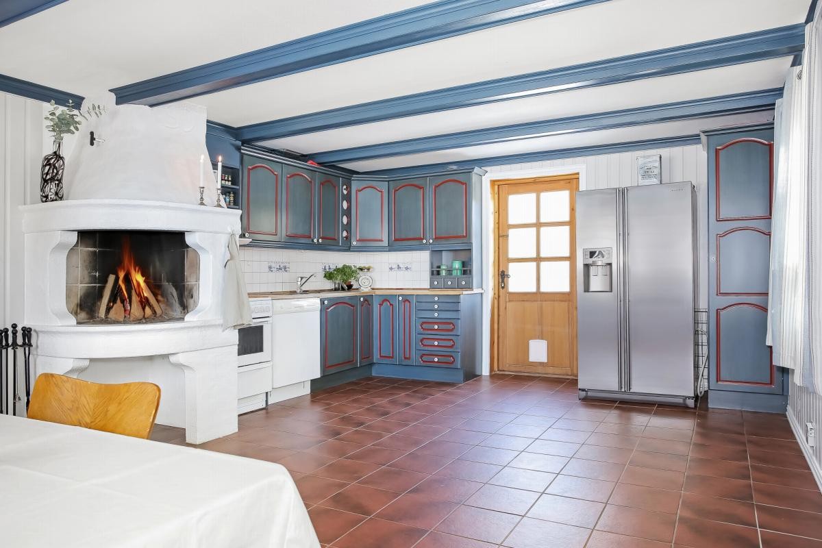 Kjøkkenet har en fin plassmurt peisovn og egen utgangsdør til egen lufteveranda Galleribilde