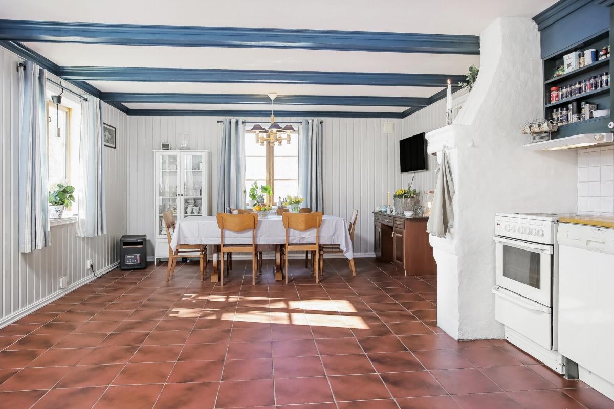 Et pent flislagt kjøkken med lyse overflater og god plass til egen sittegruppe Galleribilde