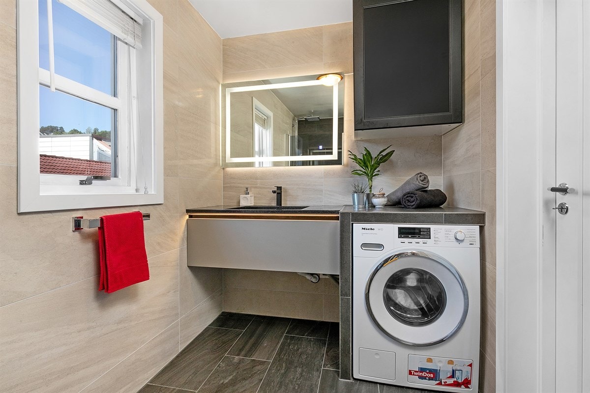 Innredningen består av en stilren skuffeseksjon med heldekkende servant, speil med belysning og et veggmontert skap. Galleribilde