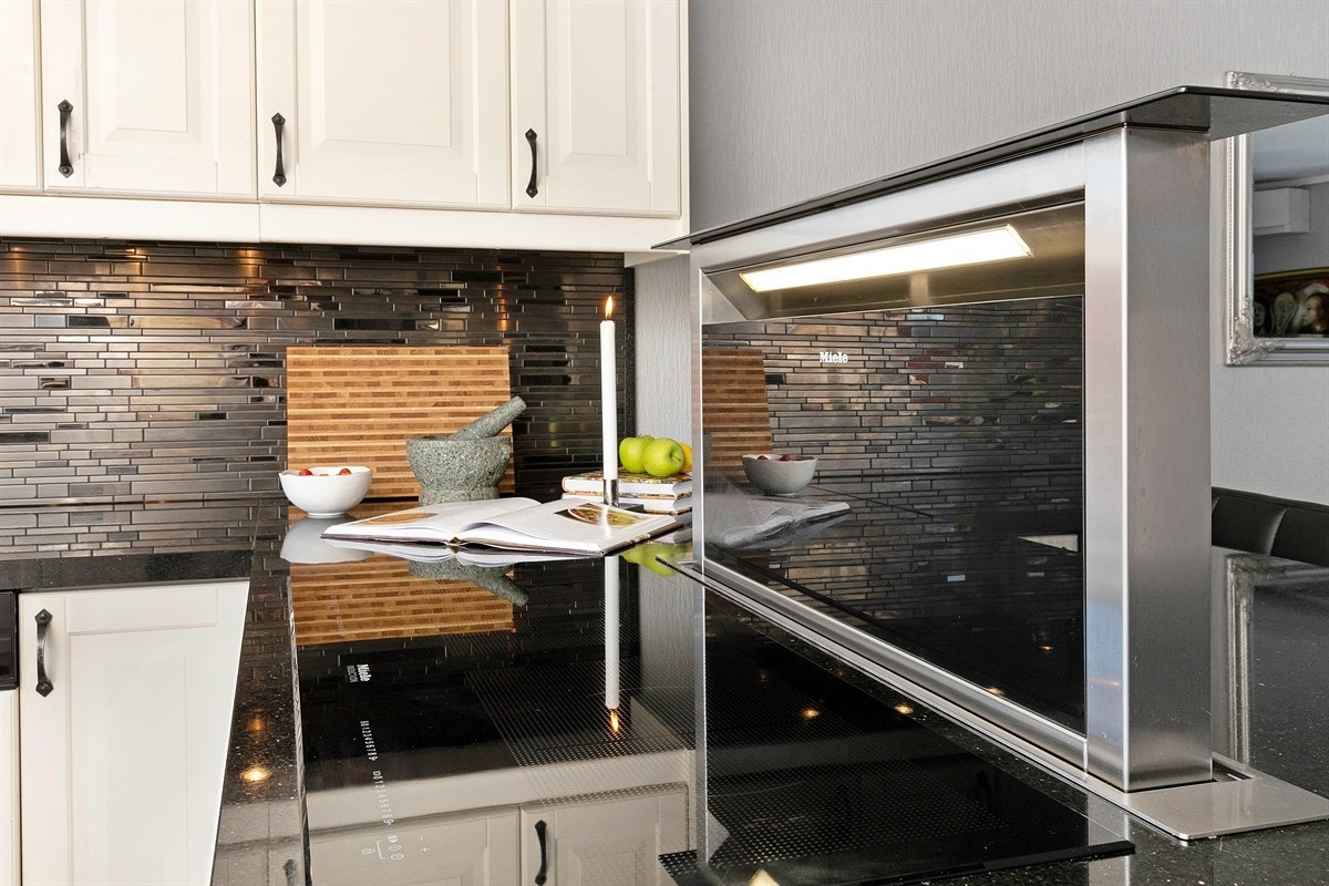 Innredningen har rikelig med skuffer og skap, fliser og lekker belysning over benk, og gode arbeidsflater til hobbykokkens glede. Galleribilde